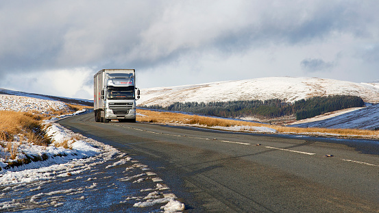 Brecon Beacons, UK: January 30, 2019: A large Daf semi truck drives on the A4059 in winter snow and dangerous icy conditions.