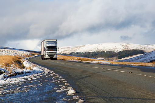 Brecon Beacons, UK: January 30, 2019: A large Daf semi truck drives on the A4059 in winter snow and dangerous icy conditions.