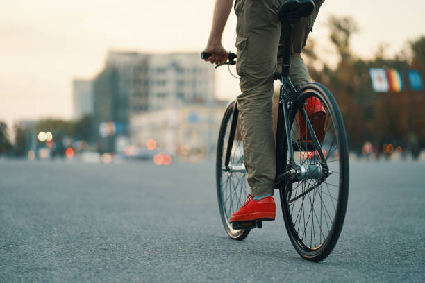 closeup de las piernas de hombre casual en bicicleta clásica en el camino de la ciudad - city bike fotografías e imágenes de stock