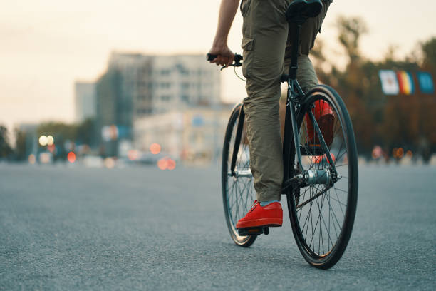 Closeup of casual man legs riding classic bike on city road stock photo
