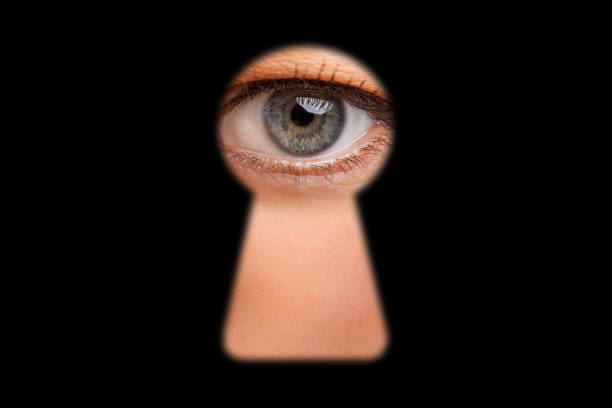 Eye of person looking through keyhole in doors Eye of person looking through keyhole in doors. Conceptual photo of spying on others. woman spying through a keyhole stock pictures, royalty-free photos & images