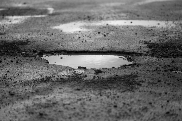 地域密着型やアスファルトに囲まれた水たまり - pot hole ストックフォトと画像