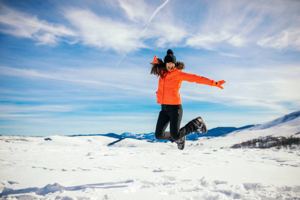Happy woman jumping on the background of snowy mountains