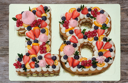 beautiful birthday cake in the shape of the number eighteen on a wooden background top view