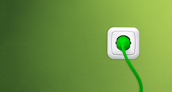 Electrical outlet with plug on green wall