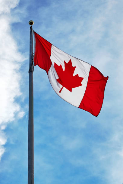 istock Canadian flag waving on blue sky background and clouds 1126665526