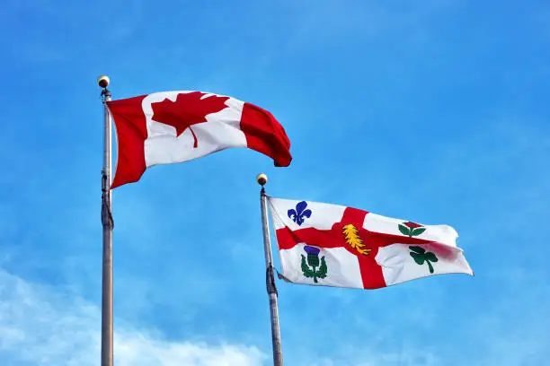 Photo of Canada flag and Montreal flag waving on clear blue sky background