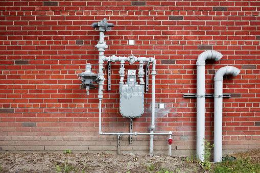 Natural gas meter gauge and pipeline on the red brick wall with copy space