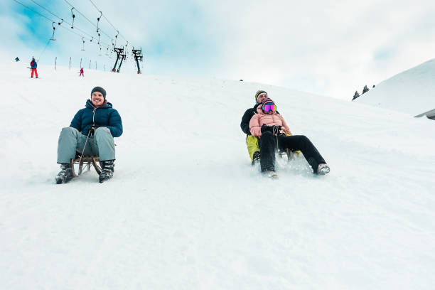 glückliche freunde spaß mit rodeln auf schnee hohe berge - tausendjährigen jugendliche rodel-wettbewerb auf weiße woche urlaub - winter sport und reisen konzept - steht auf jungs - switzerland hotel skiing people stock-fotos und bilder