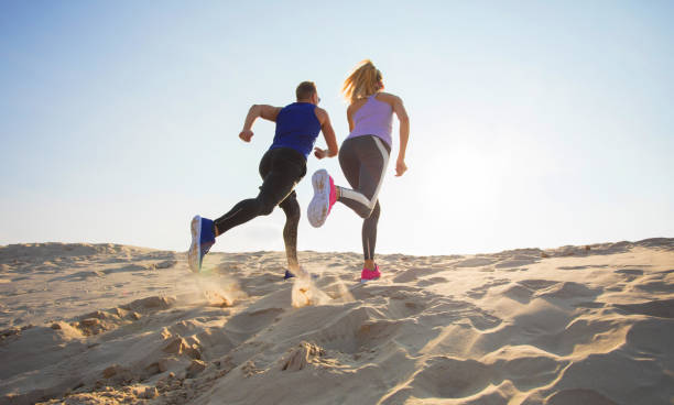 istock Man and woman running in sand 1126668899