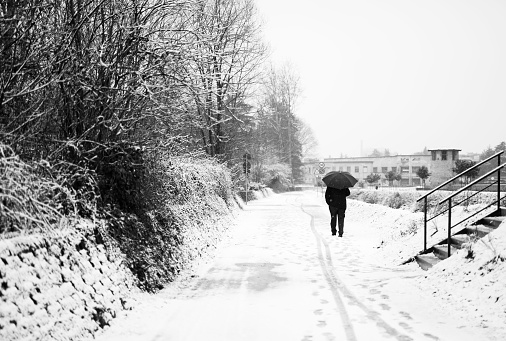 Rear view of man walking on the street during snowfall