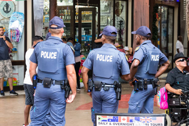 Rear view of three policemen watching over inside the UShaka Marine World in Durban, South Africa. stock photo