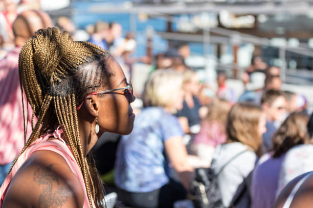 a south african black woman with braid hair and blond dyed watching a show at the amphitheater of the v & a whaft, cape town. - victoria and alfred imagens e fotografias de stock