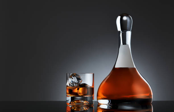 glass of whiskey with ice and a round carafe full of single malt whiskey - brandy bottle alcohol studio shot imagens e fotografias de stock