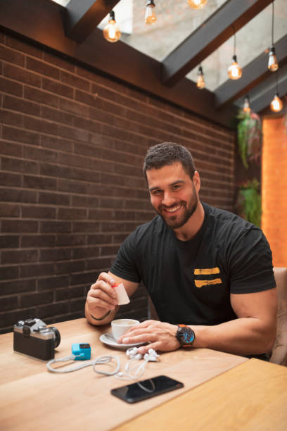 Handsome bearded man photographer Putting artificial sweetener into coffee  On coffee break in a  cafe restaurant  Freelance work