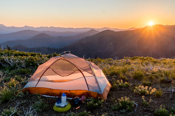 Camp Along the Pacific Crest Trail Backpacking tent glowing in the sunset light, with mountain ridges in the background shadows. Stove is setup ready to cook dinner. Lower Devil's Peak, California. pacific crest trail stock pictures, royalty-free photos & images