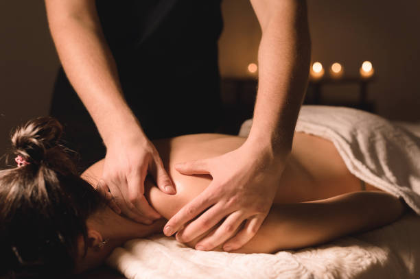 close up male manual worker doing spa massage to a young girl in a dark room - massaging massage therapist rear view human hand imagens e fotografias de stock