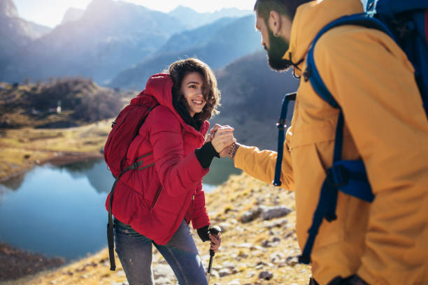 istock Helping hand - hiker woman getting help on hike happy overcoming obstacle. 1126701025