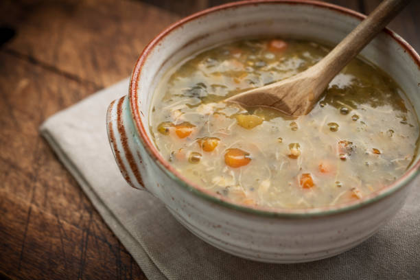 huhn und gemüse suppe in einer rustikalen schüssel vor einem dunklen holz hintergrund. - hühnersuppe stock-fotos und bilder