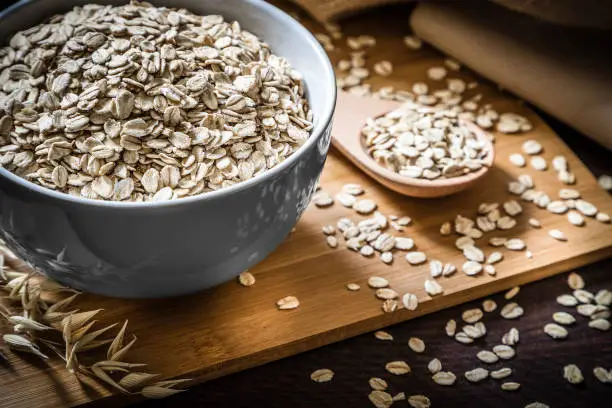 breakfast bowl full of oat flakes with a wooden spoon on wooden table