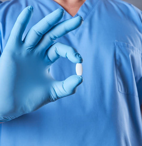 istock doctor in blue latex gloves holding a white pill 1126713471