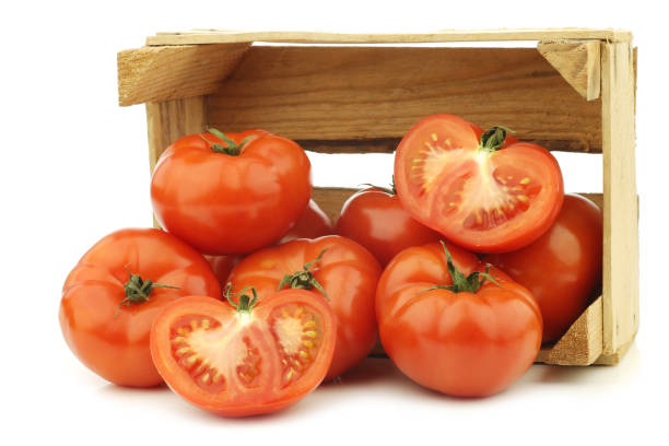 istock fresh beef tomatoes and a cut one in a wooden crate 1126714695