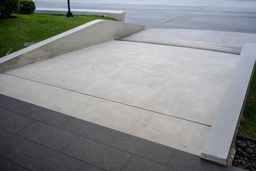 Wide ramped access, using wheelchair ramp for disabled people. Concrete ramp pathway.