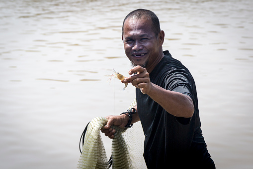 Closeup of a native fisherman practicing the art of fishing with net without boat in the river Kinabangatan, Borneo, Malaysia