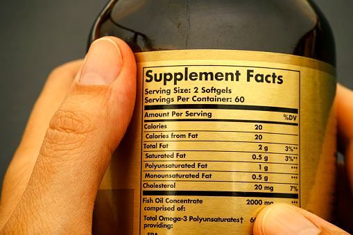 Glass jar with supplement facts in woman hands. Close-up.