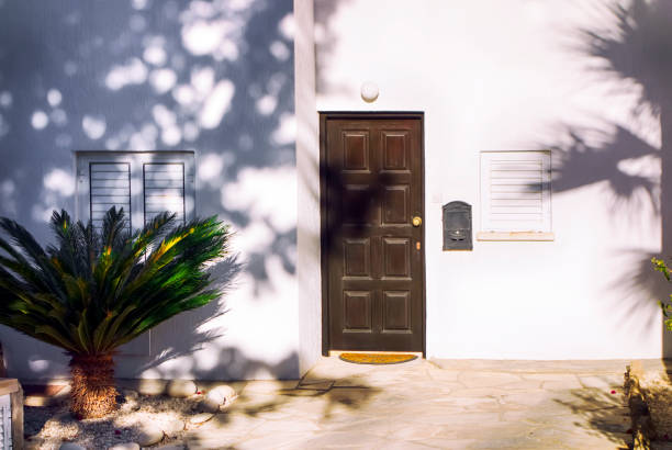 White mediterranean house with brown door, close windows and frontage.