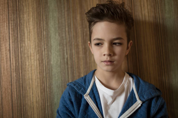 istock Serious looking boy leaning against a wall, thinking and looking downwards 1126718945