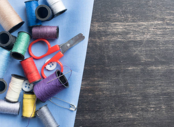 istock Sewing accessories,spools of thread with scissors on dark wood background,top view 1126721614