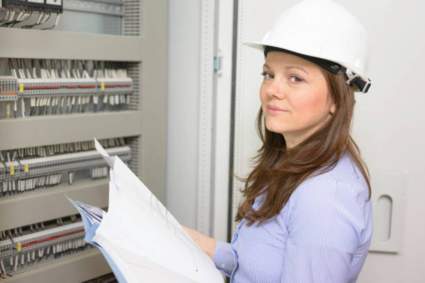 istock Woman with hardhat looking at blueprints when she working in power substation. 1126727592