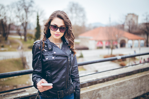 A young and attractive woman enjoying a walk in the beautiful day and use her mobile phone.