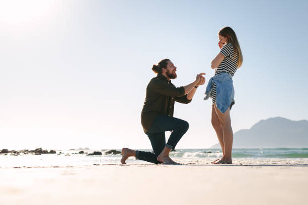 istock Man making a marriage proposal to woman at beach 1126738937