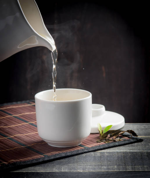 istock green tea pouring into tea cup on dark wooden backgroud. 1126738977