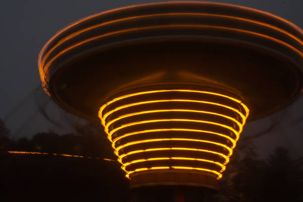 A blurry colorful chain carousel in motion at the amusement park, night illumination. The effect of bokeh and long exposure