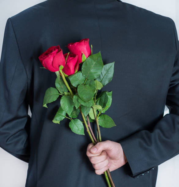 istock Elegant man holding red rose flowers in hand behind his back 1126742797