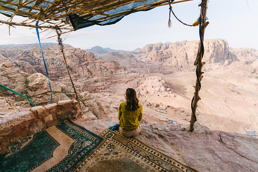 Young Caucasian woman sitting and looking at view of desert in Petra