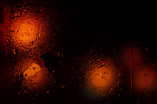 Night colorful big city lights through car windshield.Light are defocused and blurred. Focus on windshield. Underexposed photo.