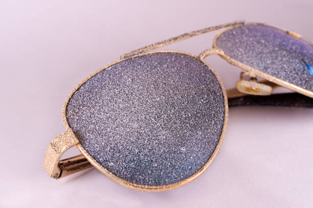 istock Sunglasses with artificial snow on white-purple background close-up view. 1126745741