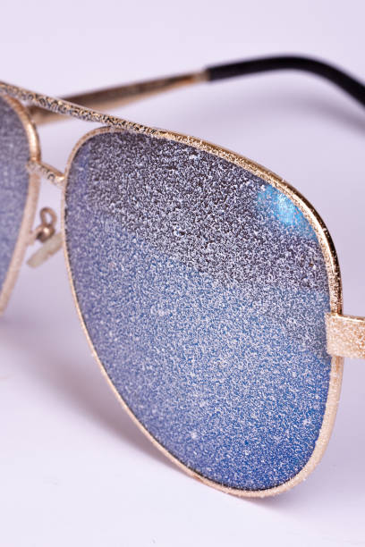 istock Sunglasses with artificial snow on white-purple background close-up view. 1126745748