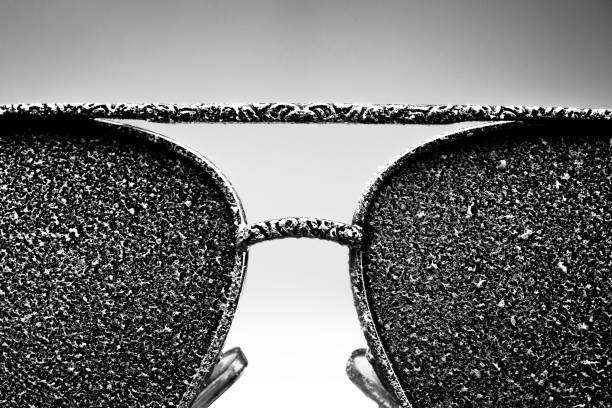 istock Sunglasses with artificial snow on white-purple background close-up view. Monochome black and white image. 1126745757