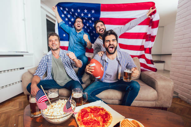 male friends watching tv and cheering sport games on sofa at home. group of friends watching american football match. - american football football food snack imagens e fotografias de stock