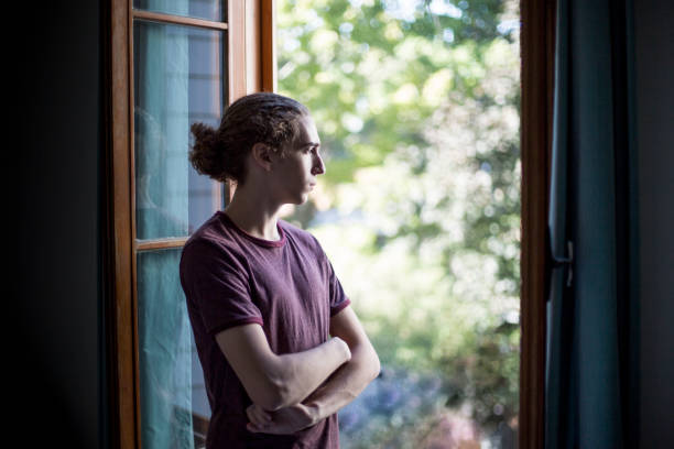istock Teenage boy looking out the window 1126748865