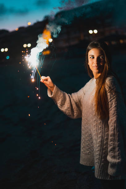 istock Young happy smiling woman holding burning Bengal light standing on sea side 1126768687