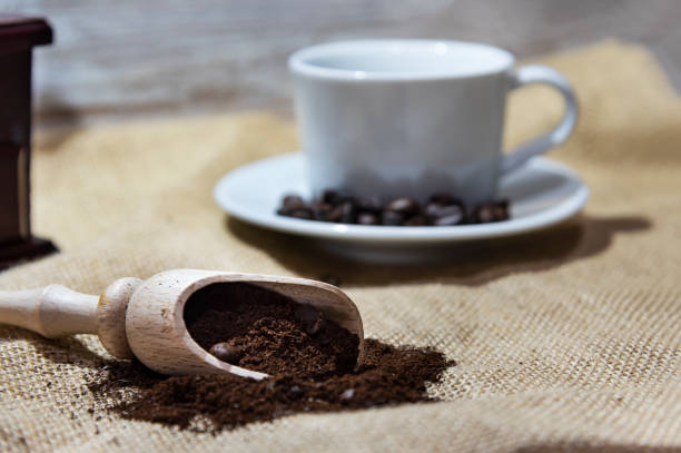 istock White cup and plate with beans, milling coffee and a wooden grinder on rustic background 1126768853