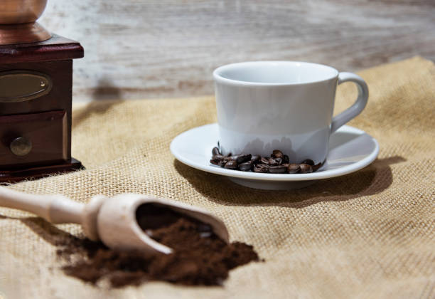istock White cup and plate with beans, milling coffee and a wooden grinder on rustic background 1126768857
