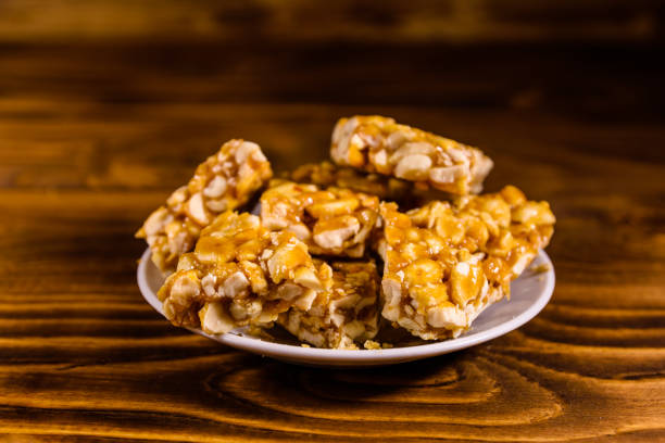 istock Ceramic plate with peanut brittles on wooden table. 1126768968