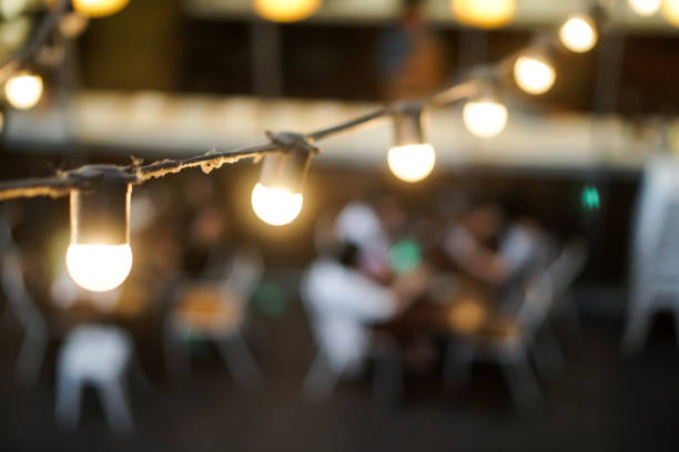 istock light bulb hang on wire outdoor restaurant blurred people background 1126779346